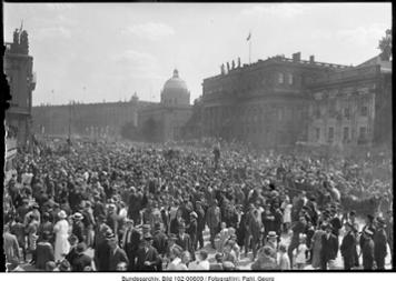 Menschenansammlung auf einer Straße, im Hintergrund der Reichstag.