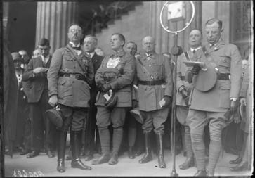 Mehrere Männe in Uniform, einer vor einem Mikrofon.